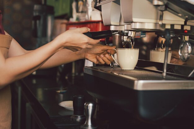 Photo female barista making cup of coffee with coffee machine in cafe