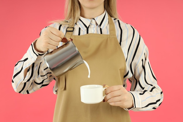 Female barista pour milk on pink background