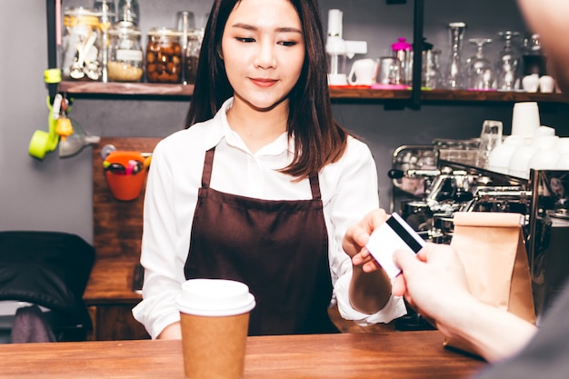 Female barista  taking a credit card from customer in coffee shop