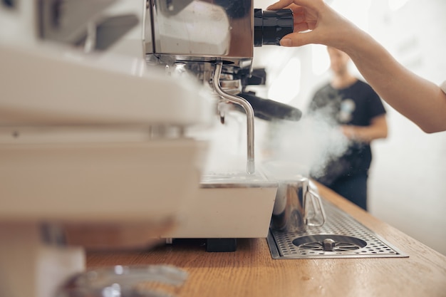 Female barista using coffee machine in cafeteria