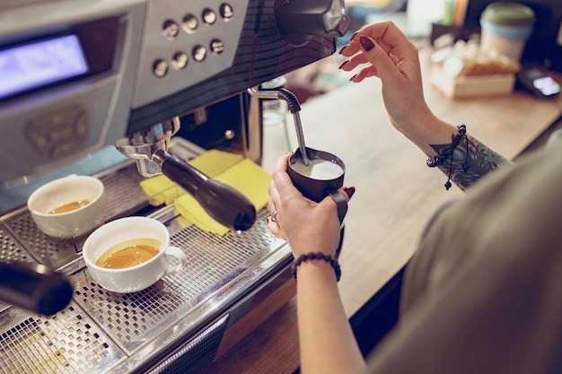 コーヒーショップでコーヒーマシンを使用して女性のバリスタ