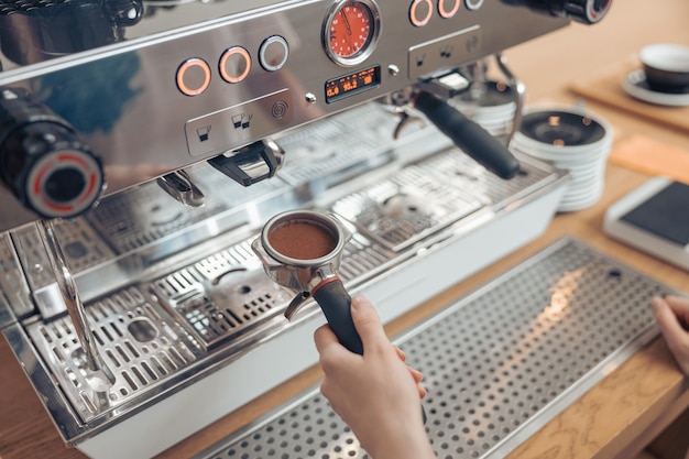 カフェテリアでプロのコーヒーマシンを使用している女性のバリスタ