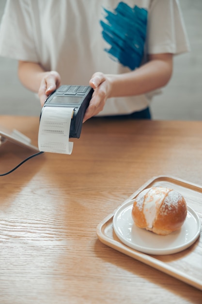 Female barista using terminal for contactless payment in coffee shop