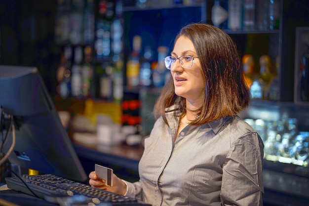 Female bartender registrating new order by cash-register. A restaurant worker registrating new order by cash-register