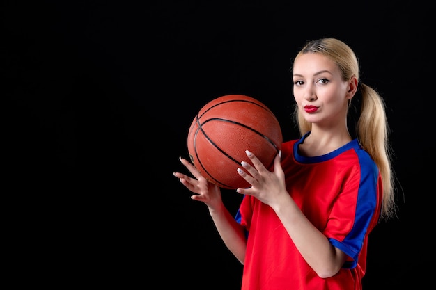 Female basketball player in sport clothes with ball on black
desk exercise game athlete