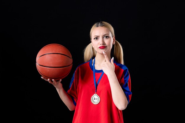 female basketball player with ball and golden medal on black background trophy winner