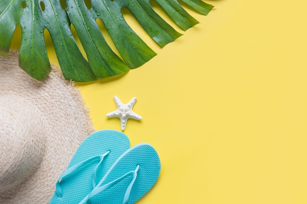 Female beach straw sunhat, outfit, flip flops on yellow. 