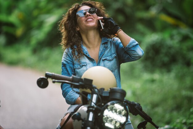 カフェレーサーバイクを運転する女性バイカー