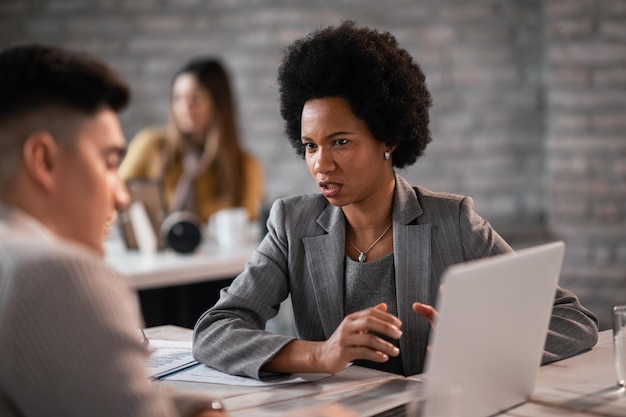 Female black insurance agent communicating with her client during a meeting at her office