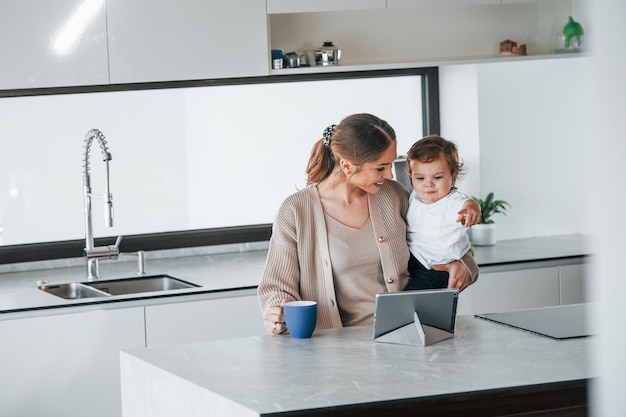 タブレットを使用して週末に自宅で一緒に彼女の子供と一緒に女性ブロガーの母親