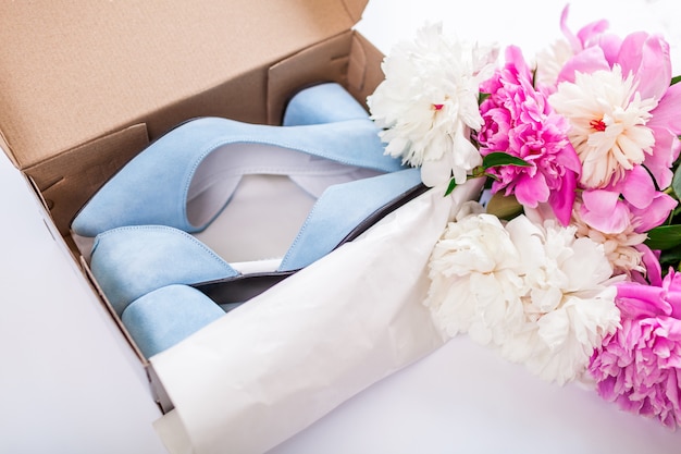 Female blue wedding shoes in box with flowers on white