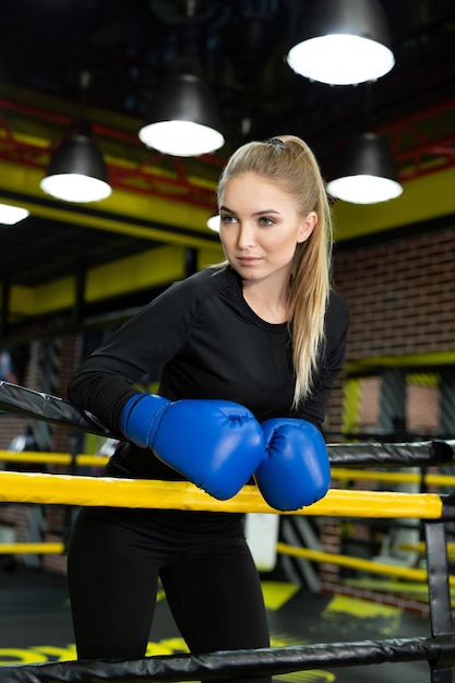 Female boxer having muscular body standing inside a boxing ring