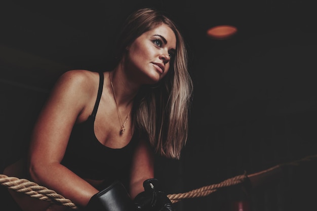 Female boxer is training in ring at punching bag in an old gym