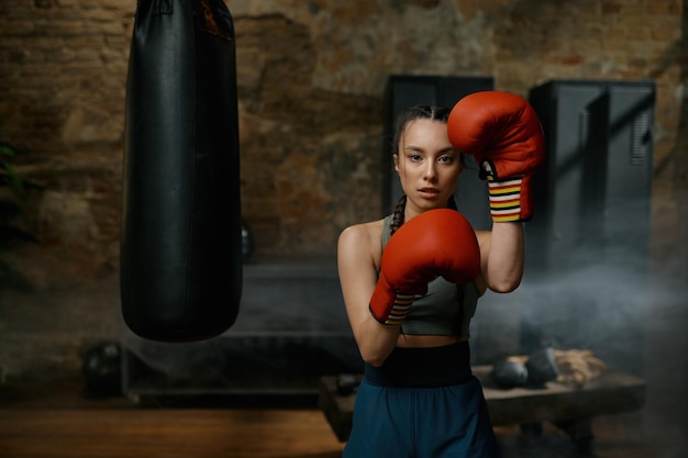 Female boxer practicing punches wearing boxing gloves looking concentrated and confidently