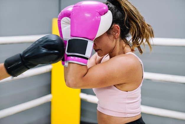 Female boxer protecting herself from her opponent\'s punches in\
the ring