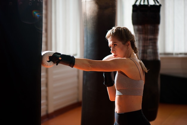 A female boxer train hard in a boxing studio.