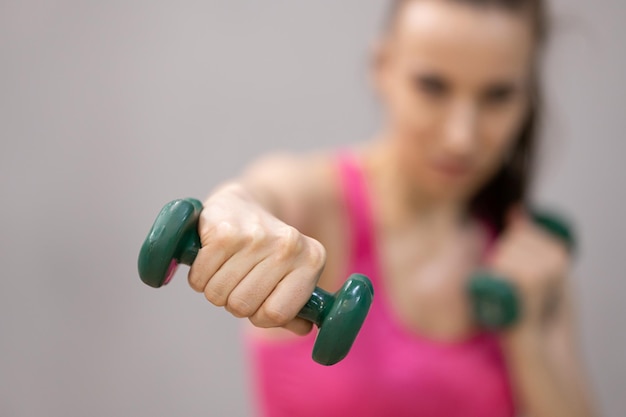 Photo female boxer trains with dumbbells on a gray background