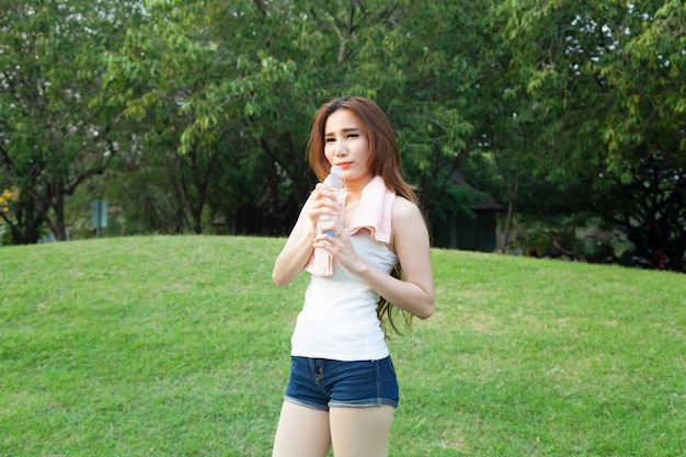 Female breaks standing and holding a bottle of water.