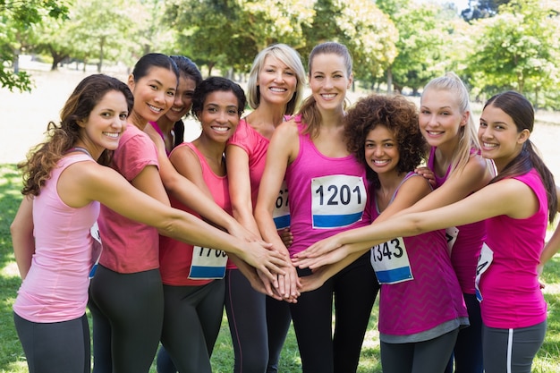 Female breast cancer marathon runners stacking hands 