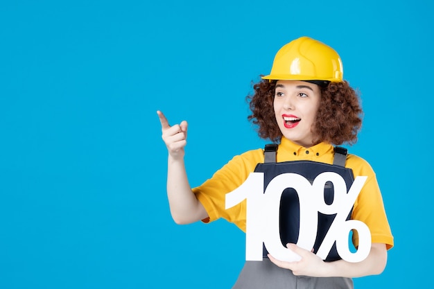 Female builder in uniform holding sign on blue