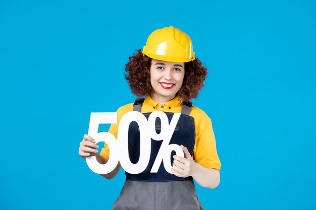 Female builder in uniform with sign on blue