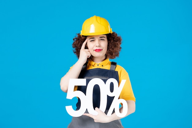 Female builder in uniform with sign on blue