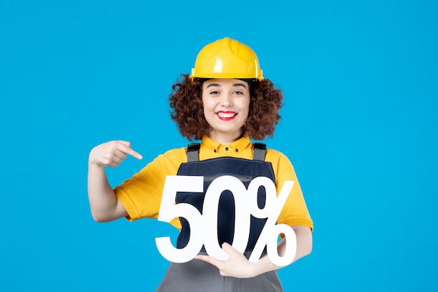 Female builder in uniform with sign on blue