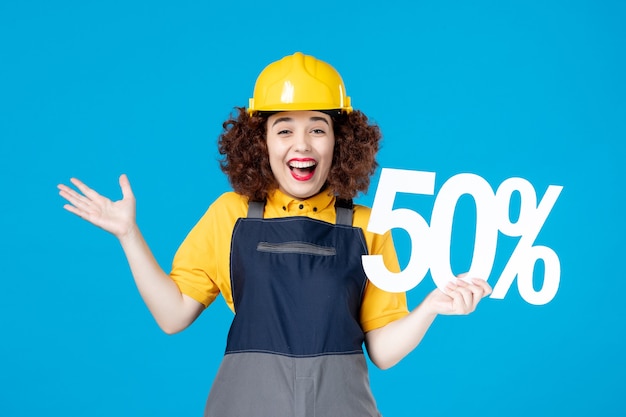 Female builder in uniform with sign on blue