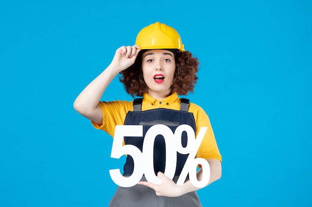 Female builder in uniform with sign on blue