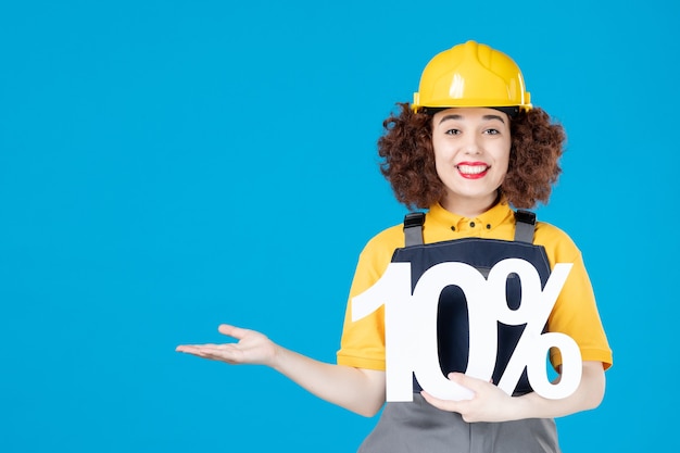 Female builder in uniform with sign on blue