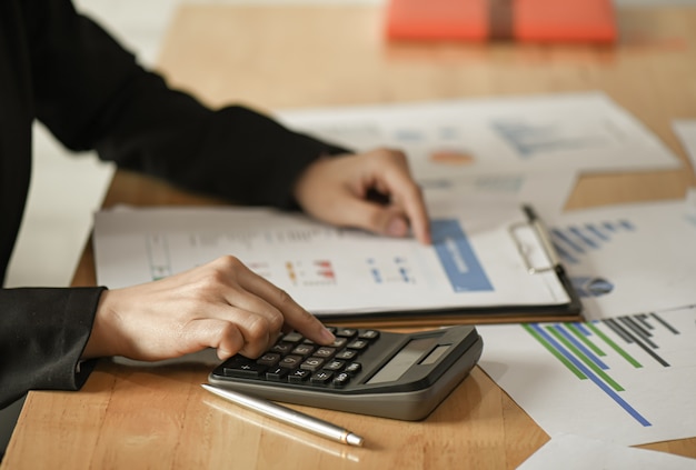 Female businessmen use a calculator , pen to plan a marketing plan to improve the quality.