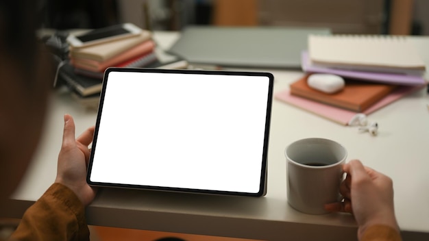 Female businesswoman reading and analysing the data at tablet screen and sipping morning coffee