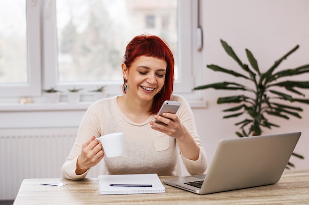 커피를 마시는 동안 스마트 폰에 여성 사업가 문자 메시지 SMS