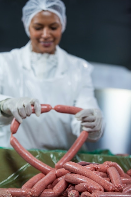 Female butcher processing sausages