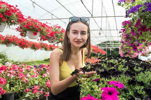 Il compratore femminile sceglie i bei fiori in una serra. stile di vita