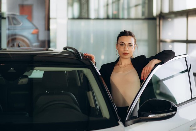 Photo female car dealer standing in showroom