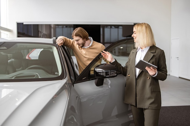 female car dealer standing with client of dealership in showroom