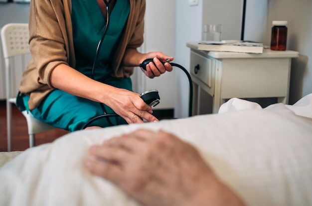 Female caregiver checking blood pressure to a senior woman at home