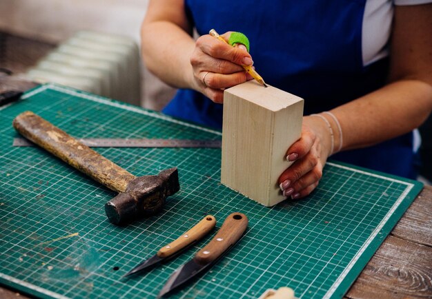 A female carpenter cuts wood with a knife in a carpentry or\
makeshift workshop dust and shavings scatter in the air