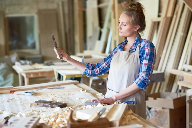 Женский плотник делает деревянные детали в мастерской