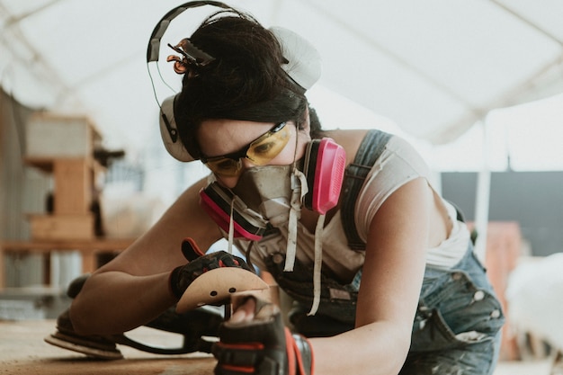 Carpentiere femminile che leviga il legname con un disco abrasivo