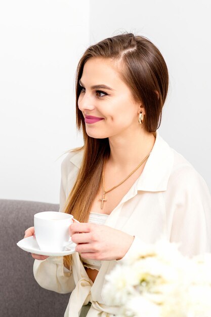 의사의 약속에 웃으면서 손에 커피 한 잔을 들고 있는 백인 여성 고객