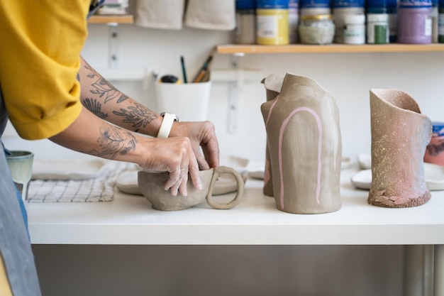 Photo female ceramist making mug in studio woman working with clay during pottery masterclass