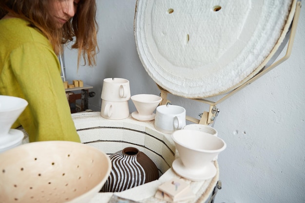 Female ceramist takes out from a kiln after firing. Master ceramist working in pottery studio. Process of creating pottery.