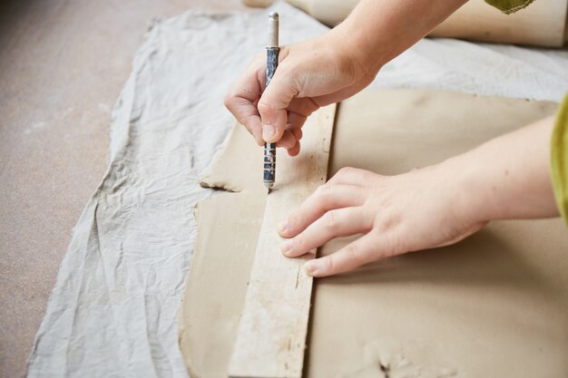 Female ceramist working in pottery studio. Ceramist's Hands Dirty Of Clay. Process of creating pottery. Master ceramist works in her studio