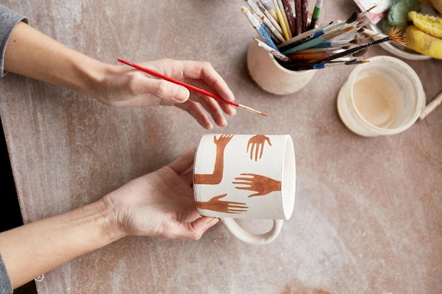 Женщина-керамист работает в гончарной мастерской. Грязные глиняные руки керамиста. Процесс создания керамики. Мастер-керамист работает в своей мастерской