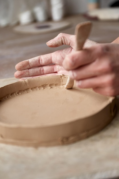 Ceramista femminile che lavora nello studio della ceramica. le mani del ceramista sporche di argilla. processo di creazione della ceramica. il maestro ceramista lavora nel suo studio