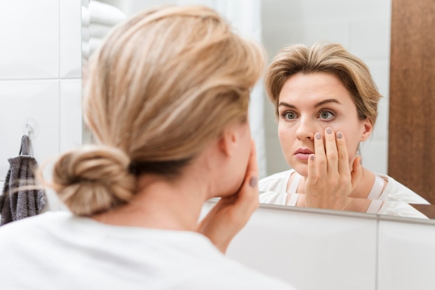 鏡で彼女の目をチェックする女性