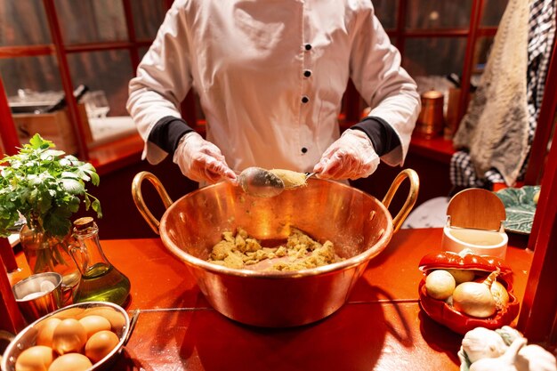 Female chef cook works in a restaurant and makes a delicious traditional dish with spoons Girl in the robe makes a Portuguese fish cutlet the codfish cake