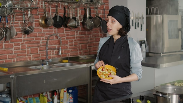 Female chef filming cooking show class for television program, using camera to record culinary content. Woman in uniform talking about professional food dish on tv vlog, gastronomy network.